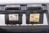 Picture of a black climate control panel and clock for a BMW E30 3-Series. Part Number stickers for the Hazard and Defrost buttons